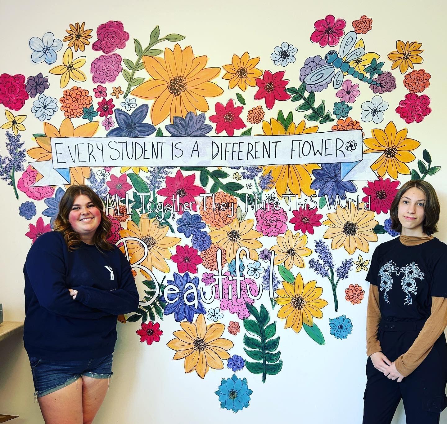 flower mural with two students standing in front