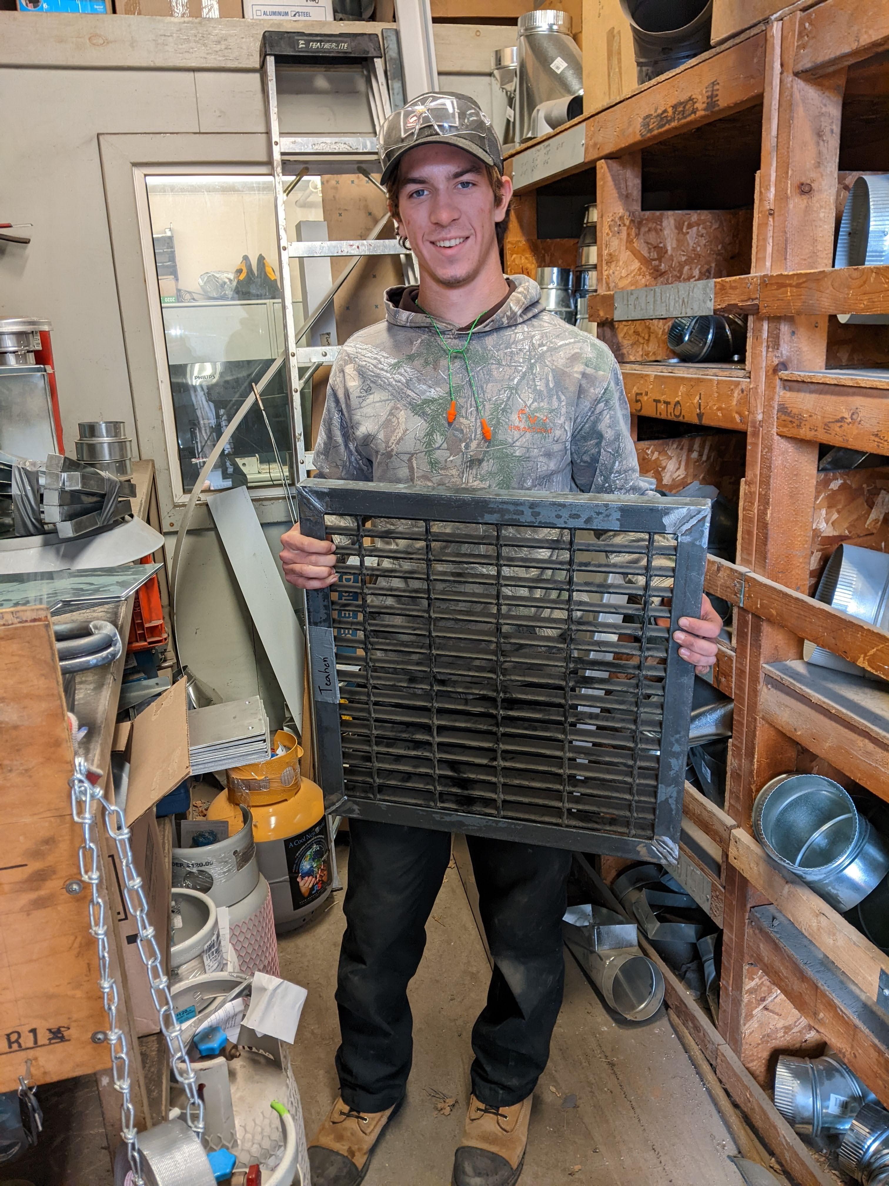 student at work holding grate he manufactured