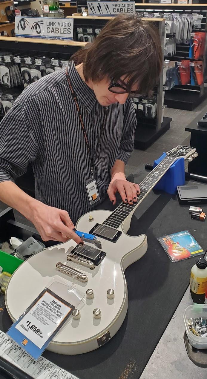 student stringing a guitar