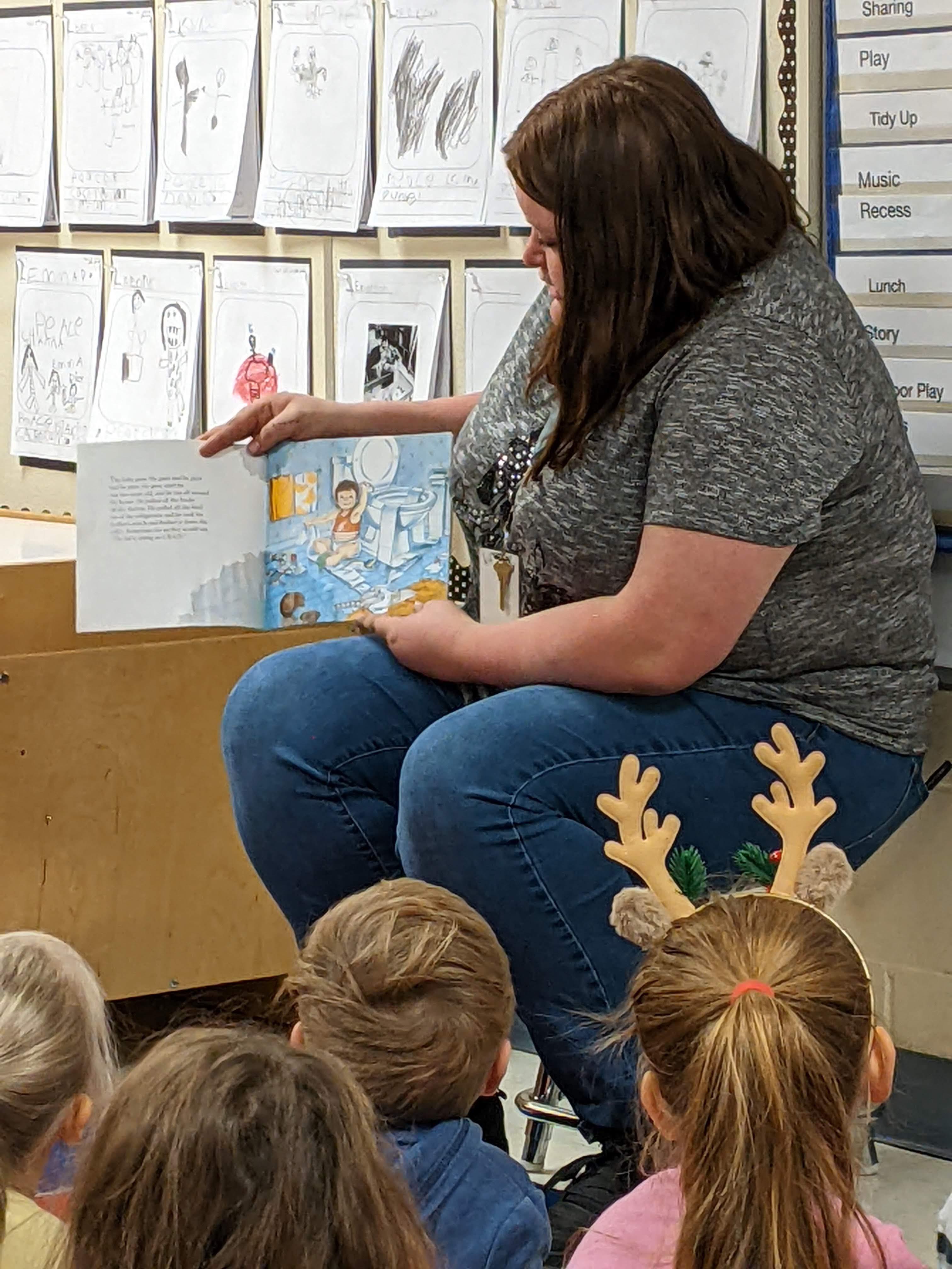 student in a class reading to kindergarten students