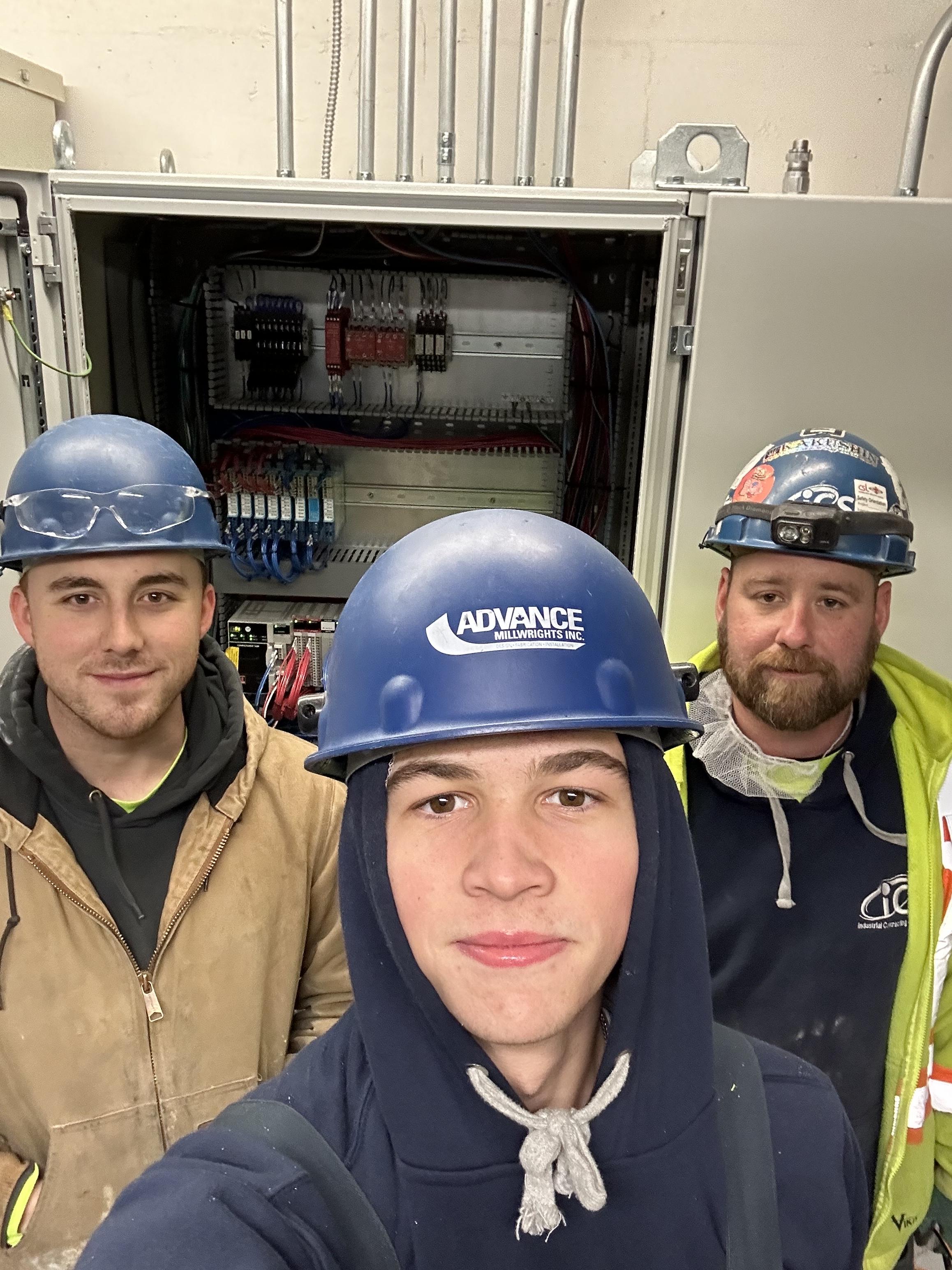 student posing with his electrician mentors