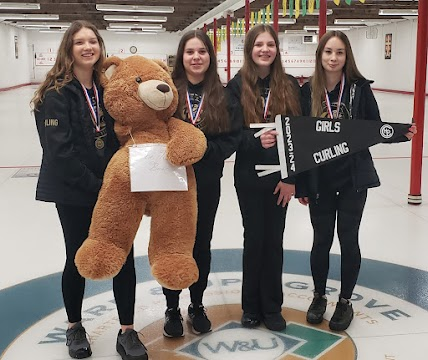 female curlers with golden bear on rink
