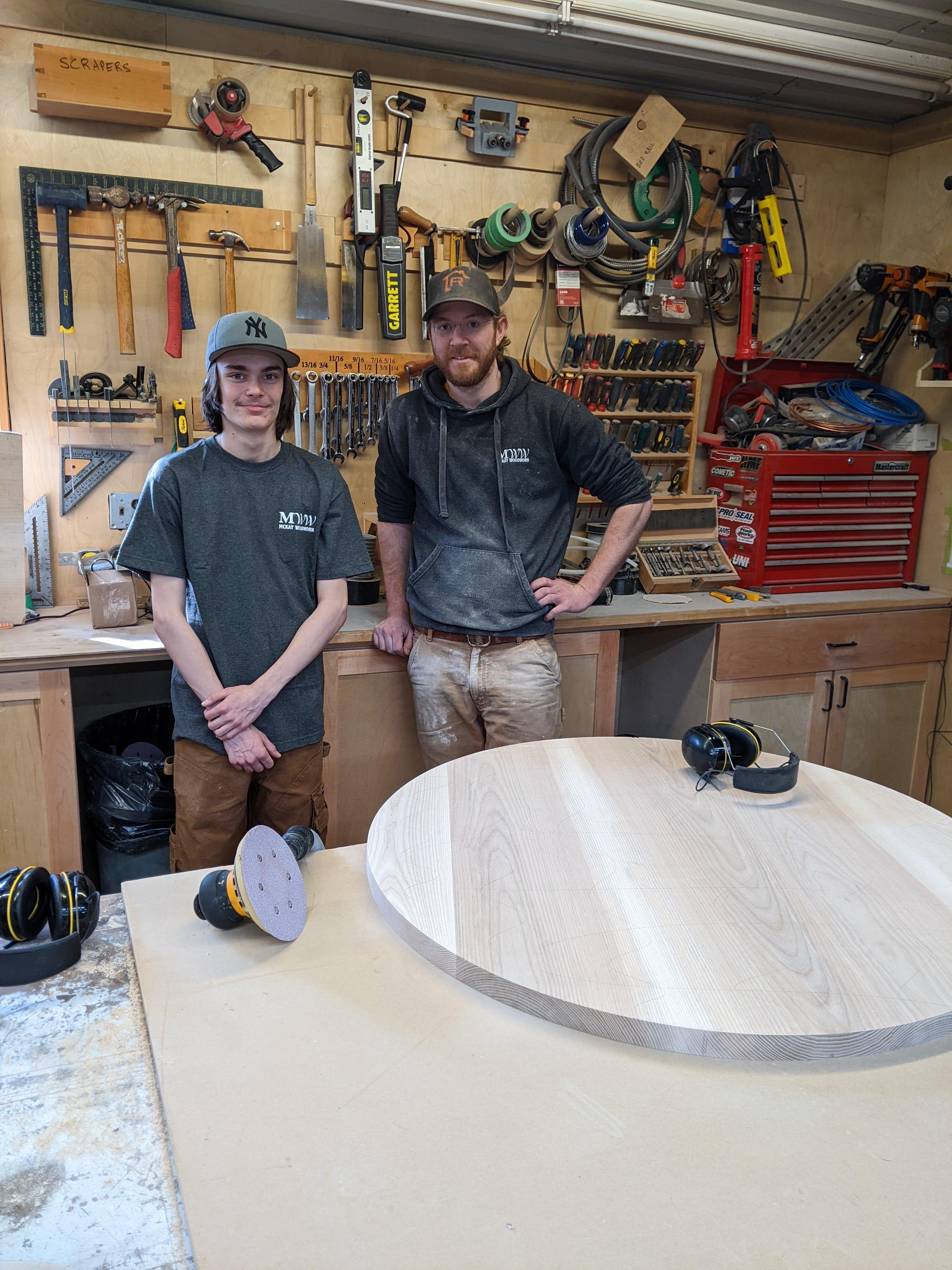 student pictured with employer in a wood shop in front of sander