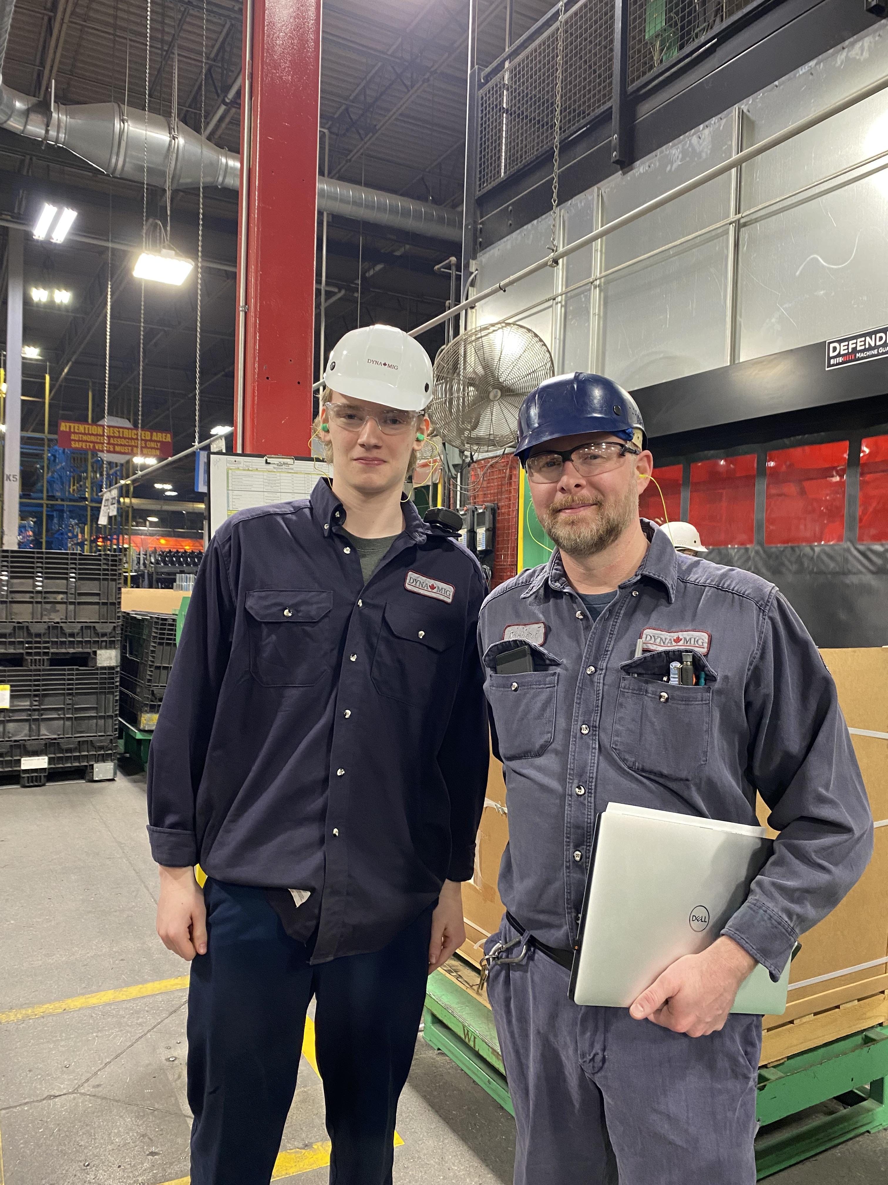 student standing with supervisor in factory