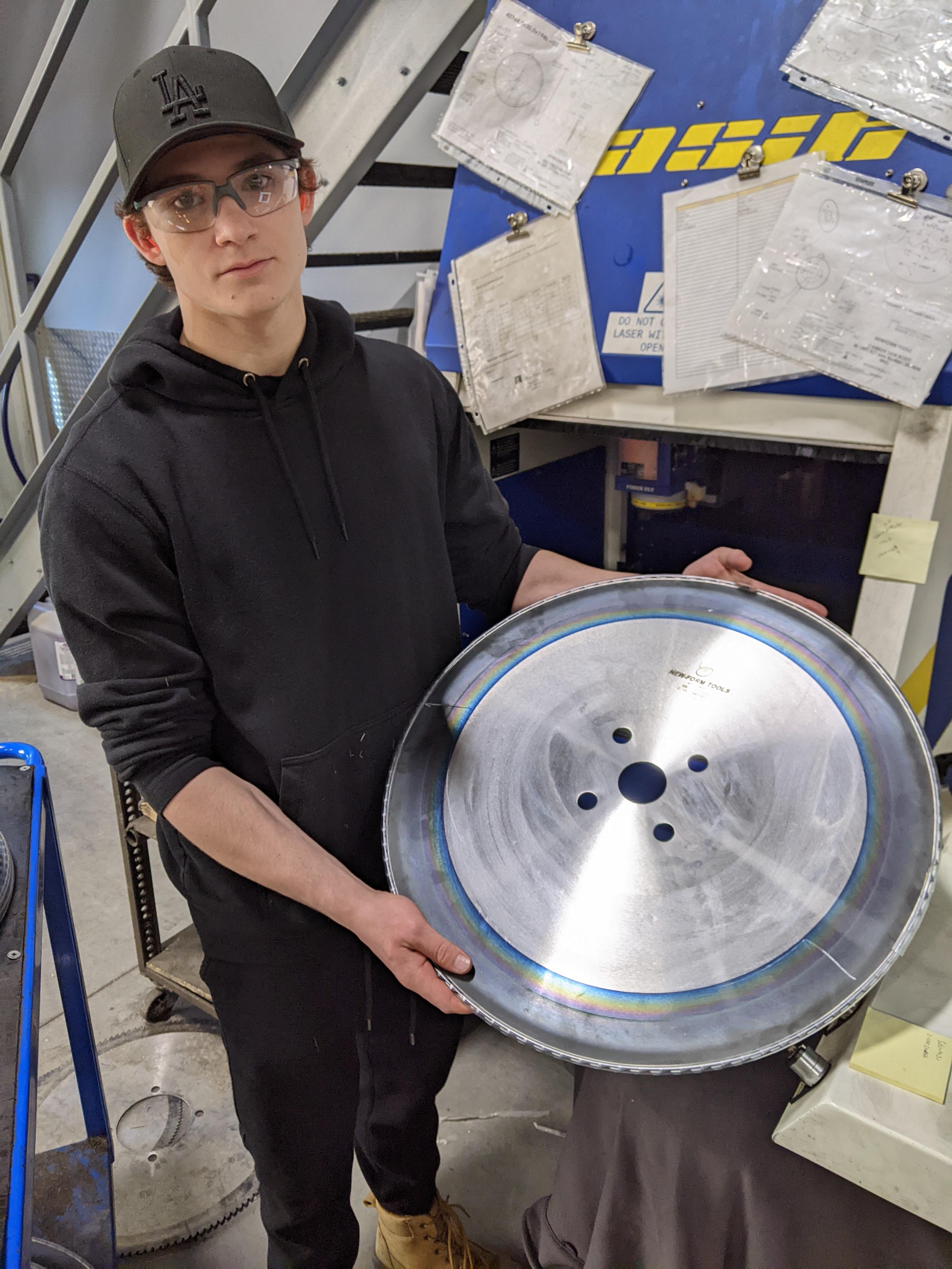 student standing holding a metal blade