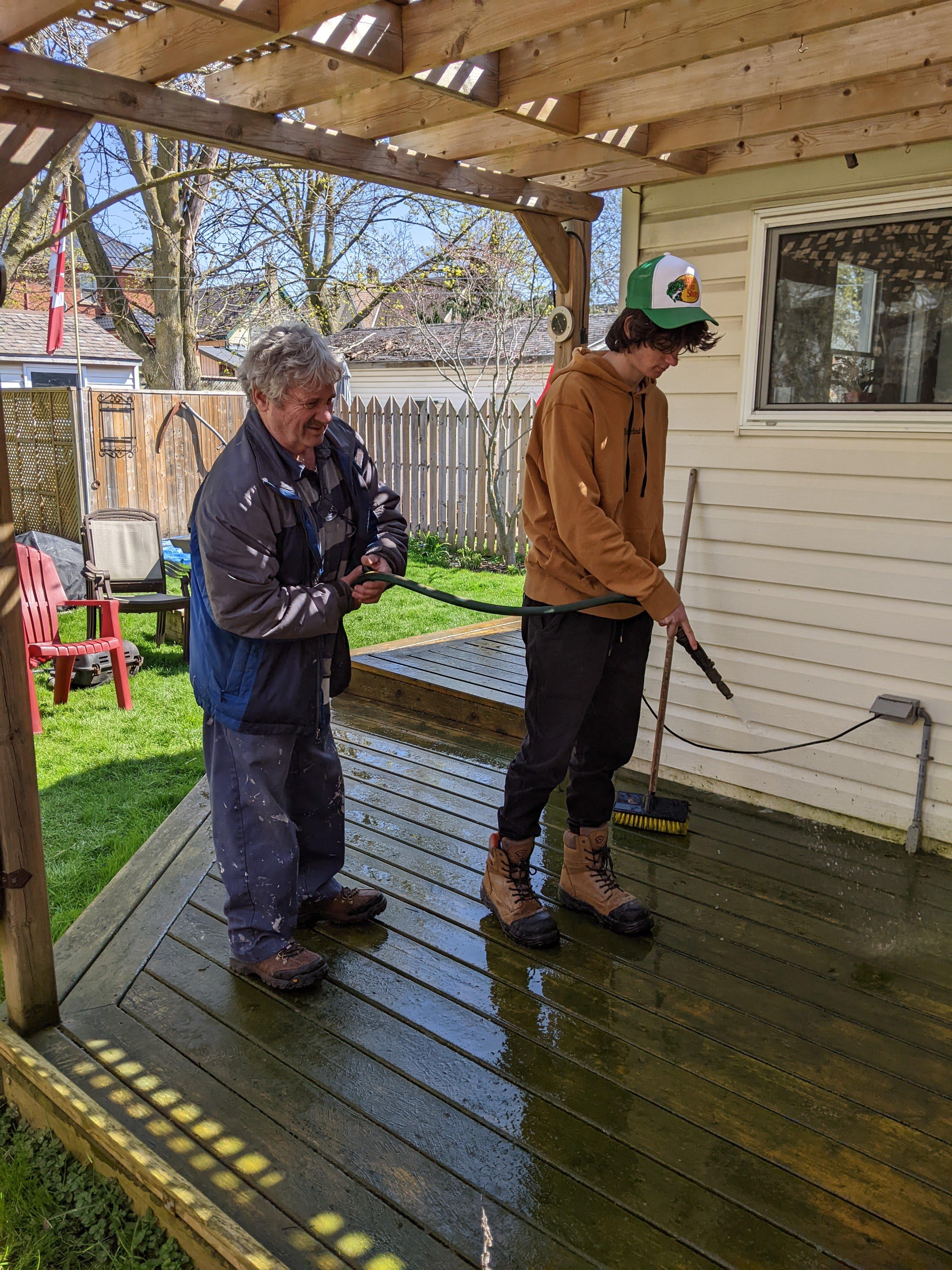 student power washing a deck with employer